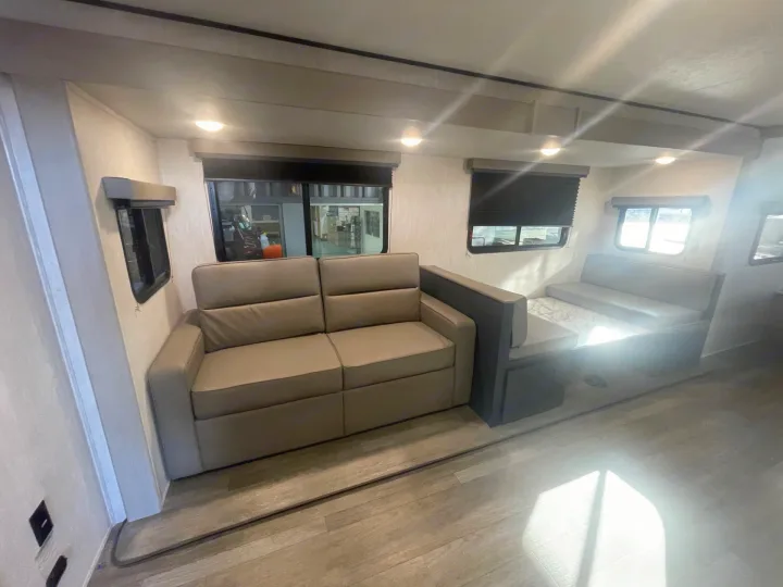 Inside this RV rental, find a modern living space with a pull-out sofa and a cozy dinette area, perfect for travel.. Coachmen APEX 284BHSS 2025