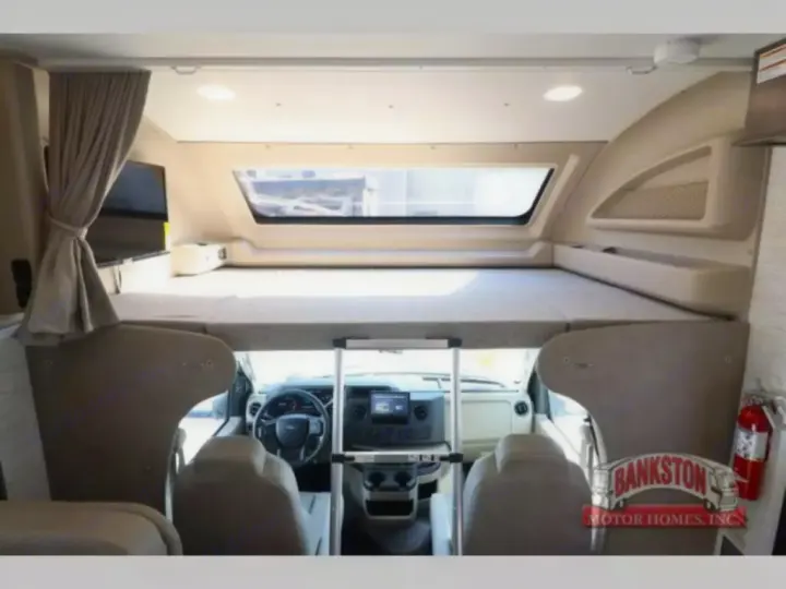 Inside an RV rental: a large cab-over bunk extends over the driver's cockpit, complete with a TV. Ready for travel adventures.. Entegra Coach Odyssey 2024