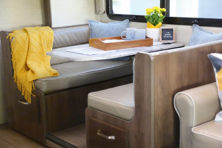 Cozy RV rental dinette: bright, modern space with a set table, comfy cushions & a yellow blanket.. Jayco Greyhawk 2019