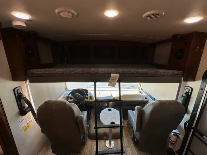 Interior of an rv rental: front cabin with driver/passenger seats, over-cab bunk, ladder, and safety features like a fire extinguisher.. Forest River Fr3 2019