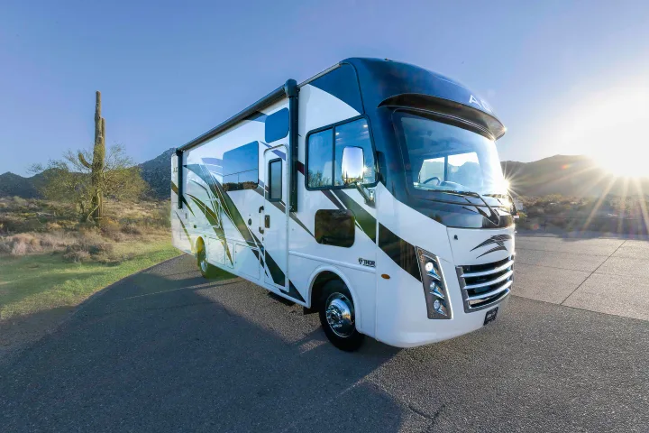 Experience desert adventures with this stunning Class A RV rental, parked in a scenic landscape with a saguaro cactus and bright sun.. Thor A.C.E. 2022