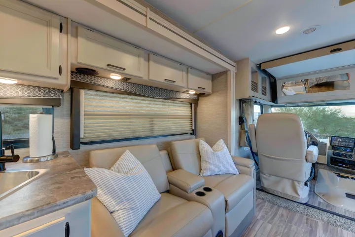 Spacious & modern RV rental interior featuring a kitchen, cozy living area with recliners, and bright cockpit.. Thor A.C.E. 2022