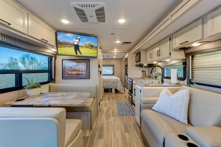 Explore this modern RV rental's spacious interior: full kitchen, dining booth, living area, and a cozy bedroom.. Thor A.C.E. 2022