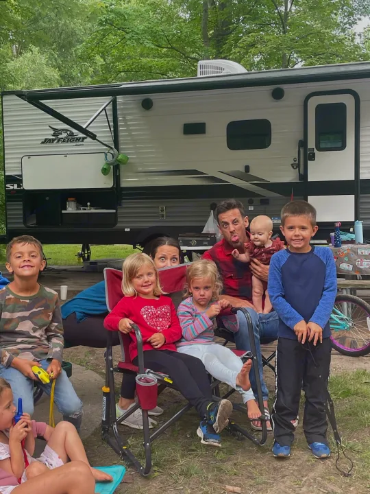 This family's RV rental adventure is off to a great start! Kids, adults, and a baby gather happily outside their camper.. Jayco Jay Flight 2022