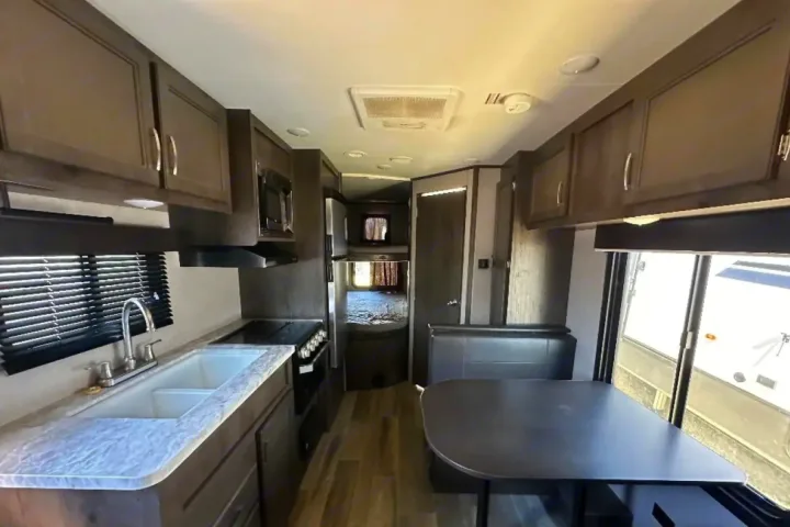 Inside a modern RV rental: well-equipped kitchen, dining booth, and rear bunk beds, ideal for family travel.. Jayco Jay Flight 2022