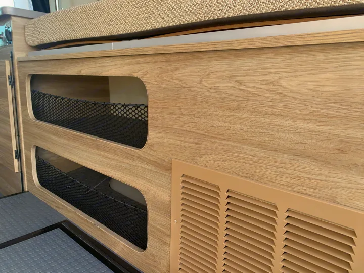 RV rental: Interior showing light wood cabinets with mesh storage pockets, an upholstered cushion, and floor vent.. Winnebago Solis 59PX 2025