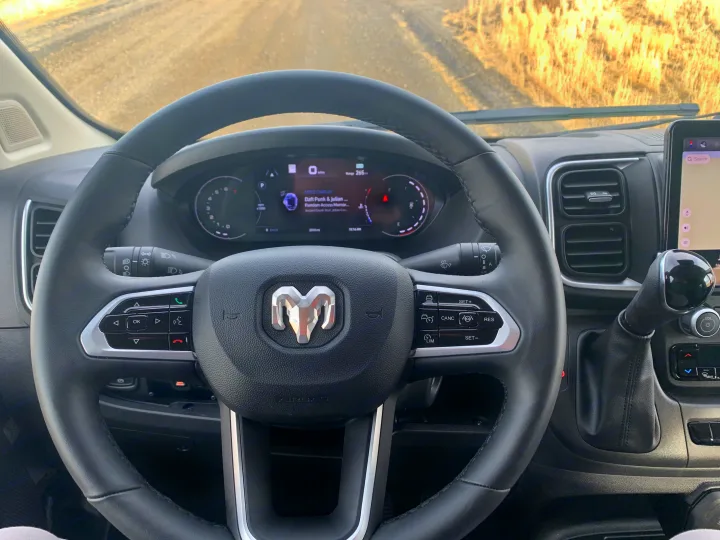 Inside an RV rental, showing the driver's perspective: steering wheel, digital dashboard with Apple CarPlay, and navigation.. Winnebago Solis 59PX 2025