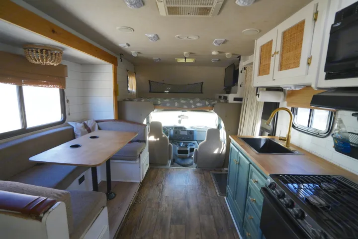 Spacious RV rental interior featuring a full kitchen, dining area with table, and cozy overhead bunk. Ideal for road trips.. Jamboree Sport 2011