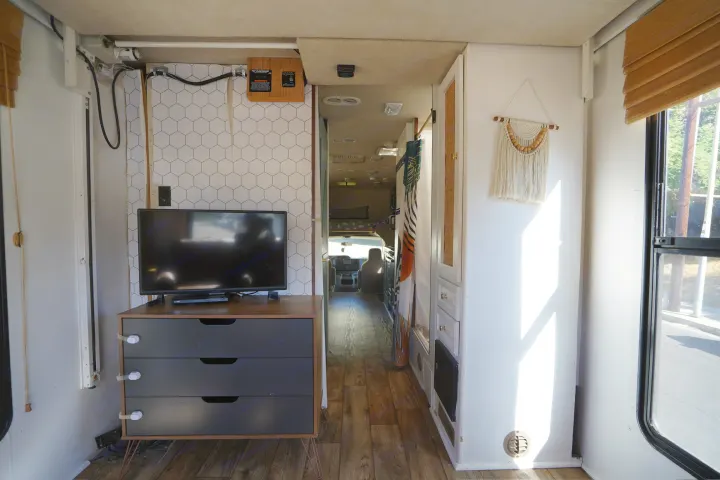 A cozy rv rental interior from rear to front, showing TV, a patterned wall, and organized space with a window.. Jamboree Sport 2011