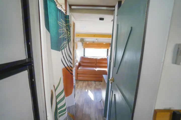 Explore this RV rental's inviting interior! Features a comfortable brown couch, wooden floors, and bright natural light.. Jamboree Sport 2011