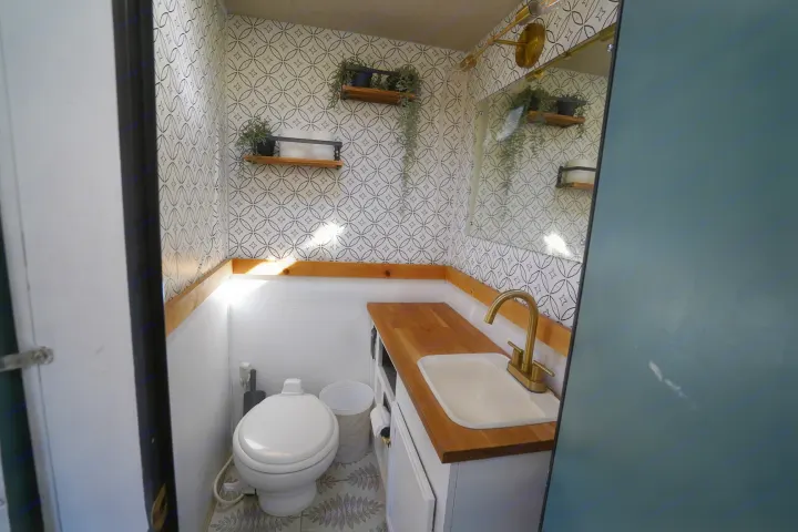 Bright, stylish RV rental bathroom features patterned wallpaper, wood counter, sink, and toilet for compact living.. Jamboree Sport 2011
