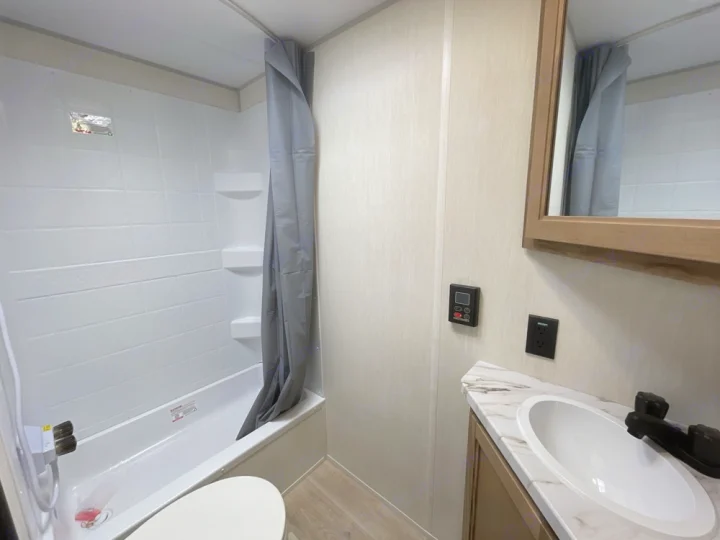 Compact RV rental bathroom with shower, toilet, and sink. Ideal for travel trailer adventures.. Forest River 17JW 2025