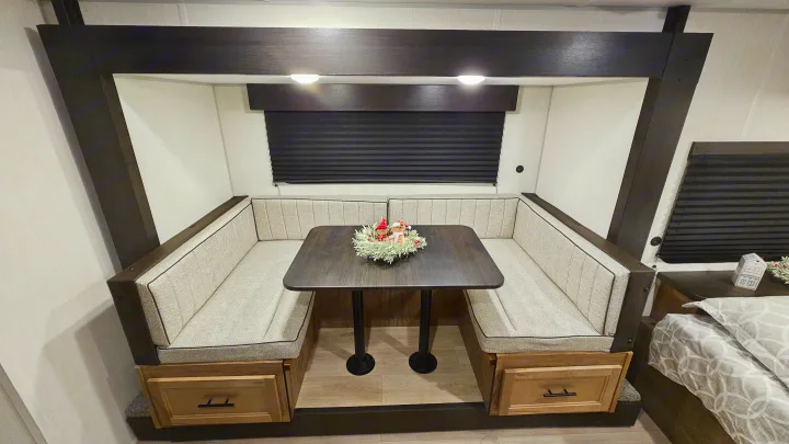 Modern RV rental dinette with comfortable booth seating, a dark table, and cozy holiday decor.. Forest River 17JW 2025