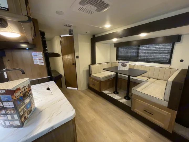 Modern RV rental interior: U-shaped dinette, kitchen, and bunk beds, perfect for family road trips.. Forest River 17JW 2025
