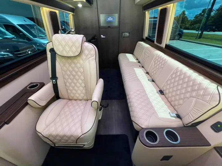 Luxury rv rental interior with plush, quilted leather captain's chair & bench seating, wood accents & cup holders.. Midwest Automotive Designs Day Cruiser 2024
