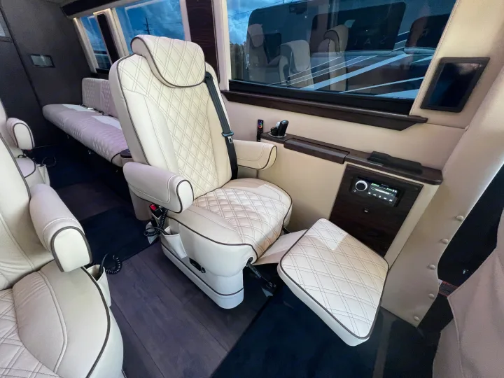 Luxury RV rental interior with cream quilted leather seating, extendable footrest, and integrated entertainment controls for ultimate travel comfort.. Midwest Automotive Designs Day Cruiser 2024