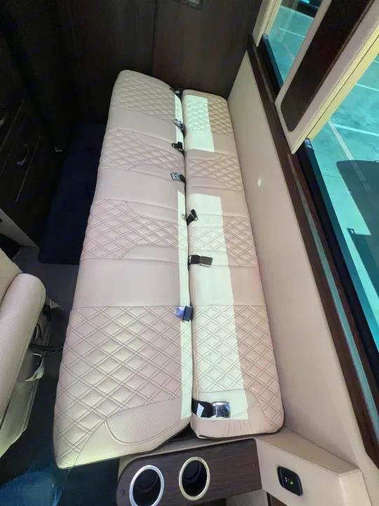 Inside an RV rental: Beige quilted seating area with seat belts and cupholders, perfect for trips.. Midwest Automotive Designs Day Cruiser 2024
