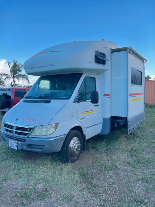 White Winnebago View RV rental parked on grass, ready for your next adventure. Visible side slide-out and California plate.. Winnebago View 2005