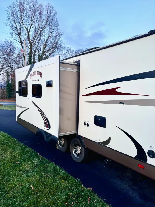 An RV rental, a white Starcraft Travel Star, is shown with its side slide-out extended while parked on asphalt.. Starcraft Travel Star 2015
