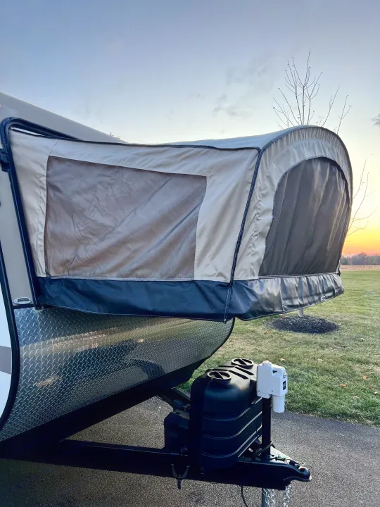 Front of an RV rental hybrid travel trailer with its pop-out tent extension deployed against a sunset sky.. Starcraft Travel Star 2015