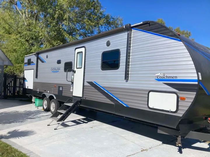 Coachmen Catalina travel trailer RV, grey/black with blue accents, parked on concrete. Ideal for rv rental adventures.. Coachmen Catalina 2022