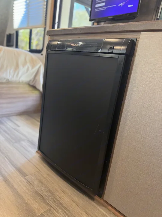Compact, black Dometic RV refrigerator, with automatic temperature control, installed in an RV rental.. Winnebago Minnie Winnie 2022