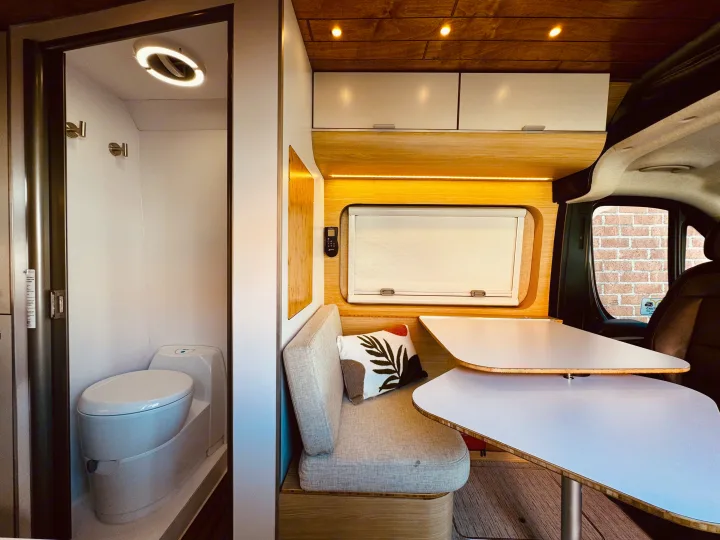 Modern RV rental interior: compact bathroom, cozy bench, and unique dining tables for comfortable travel.. Noovo Lite 2023