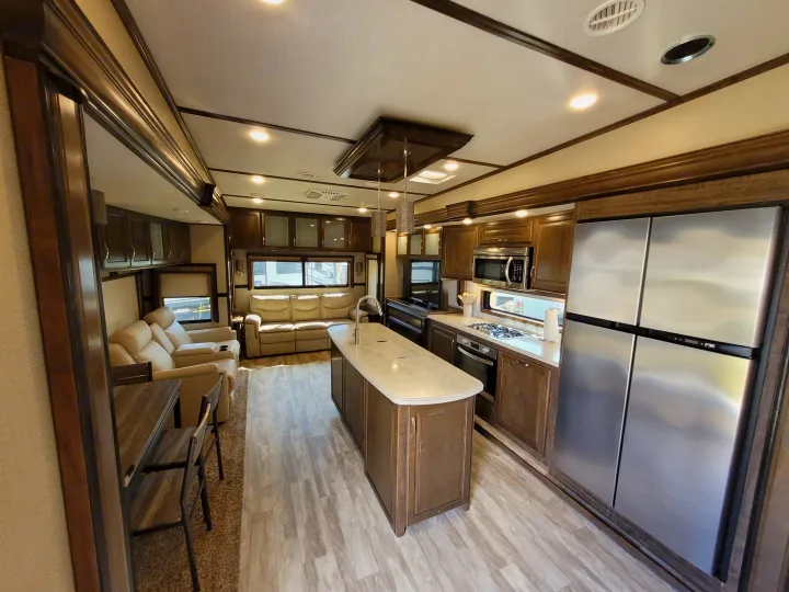 Modern rv rental interior showcasing a full kitchen with island and stainless steel appliances, plus a comfy living area.. Grand Design Solitude 2019