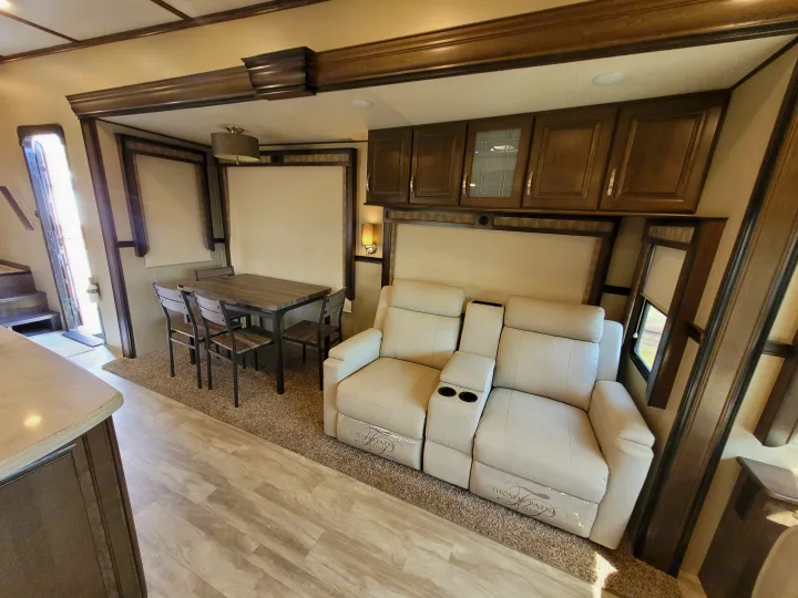 Modern RV rental interior with a cozy dining area, comfortable recliners, and overhead storage for your travels.. Grand Design Solitude 2019