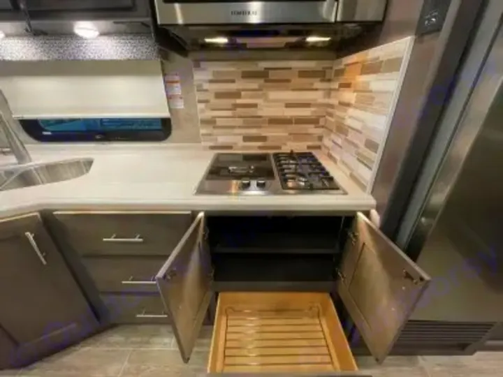 This RV rental kitchen boasts a modern sink, stovetop, microwave, and accessible under-counter storage with a pull-out rack.. Thor Miramar 2022