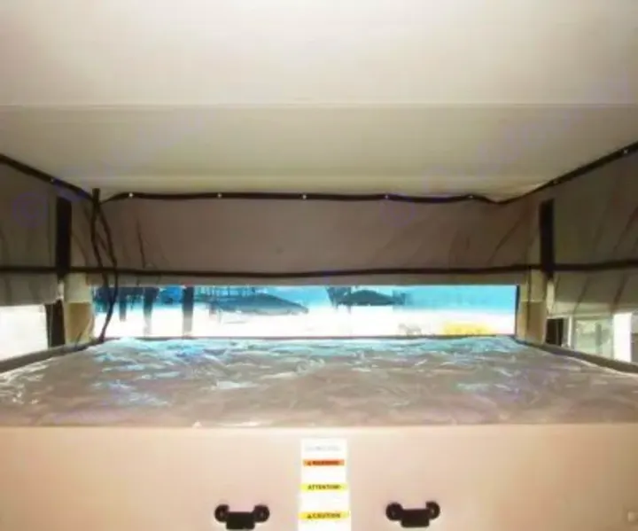 Inside an RV rental: a comfortable bunk bed with a panoramic window view of the bright outdoors. Great for camping trips.. Thor Miramar 2022