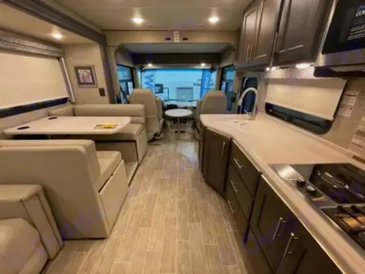 Explore this clean, modern RV rental interior with a full kitchen, dining booth, and front seating area.. Thor Miramar 2022
