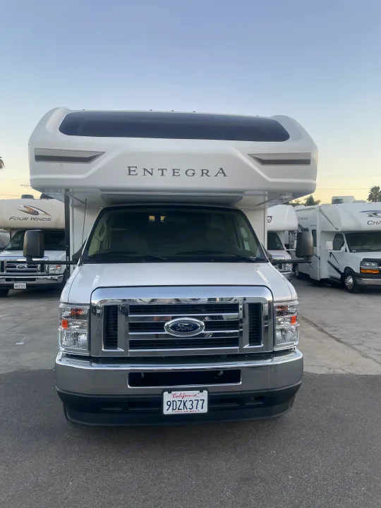 White Entegra Class C RV rental on a Ford chassis. Parked with other motorhomes in a lot. CA plate 9DZK377.. Thor Chateau 2022