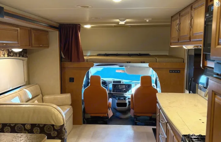 Inside a comfortable RV rental: cockpit, overhead bunk, sofa, and kitchen areas are clearly visible.. Winnebago Minnie Winnie Premier 2015