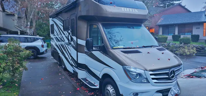Brown & white Tiffin motorhome RV rental parked on a residential street. White SUV & autumn leaves visible.. Wayfarer Wayfarer Motorhome 2018