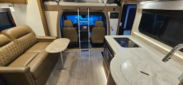 Spacious RV rental interior featuring a cozy sofa, kitchen, and front cockpit with a bunk ladder.. Wayfarer Wayfarer Motorhome 2018