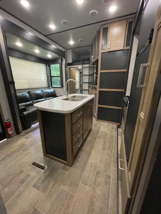 Spacious rv rental interior featuring a modern kitchen island, comfortable lounge, and bunk bed area. Ideal for travel.. Dutchmen 3586 2019