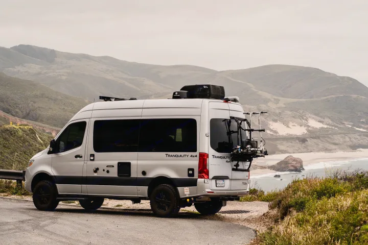 Silver Tranquility 4x4 rv rental parked on a coastal road overlooking mountains & ocean. Ideal for adventure travel.. Thor Tranquility 2023