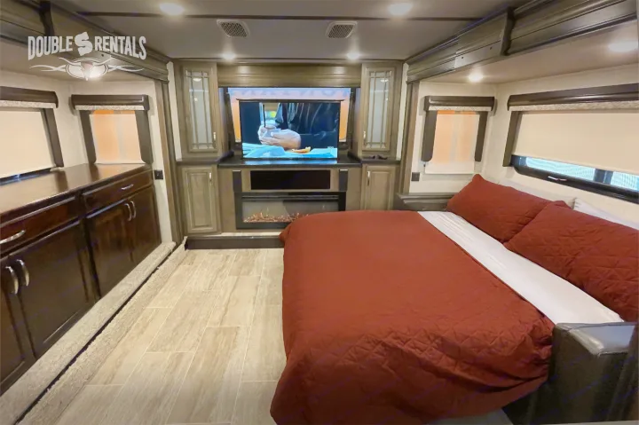 Spacious and cozy RV rental bedroom with a large bed, TV, and fireplace. Perfect for a comfortable getaway.. Keystone Montana 2019