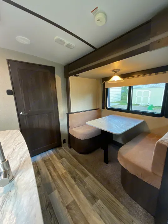 Cozy RV rental interior featuring a bright dinette, comfy benches, table, and kitchen counter.. Keystone RV Outback Super-Lite 2018
