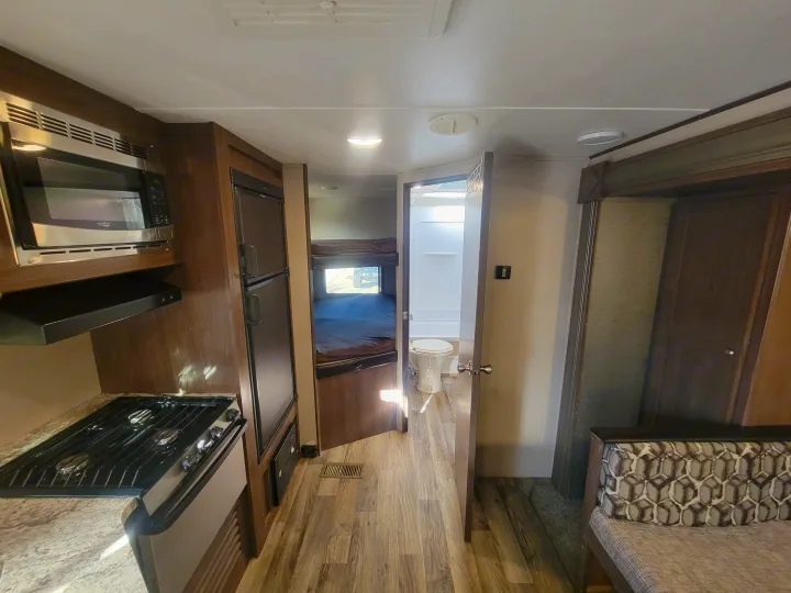 Spacious RV rental interior featuring a full kitchen, bunk beds, a functional bathroom, and cozy living area.. Keystone RV Hideout LHS 2019
