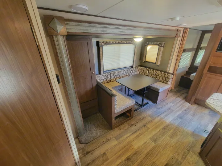 Spacious RV rental dinette and interior storage, featuring comfy booths, a movable table, and bright windows.. Keystone RV Hideout LHS 2019