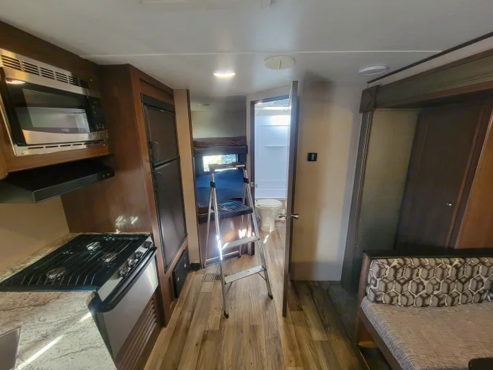 RV rental interior featuring a compact kitchen with stove and microwave, bunk beds, and a bathroom.. Keystone RV Hideout LHS 2019