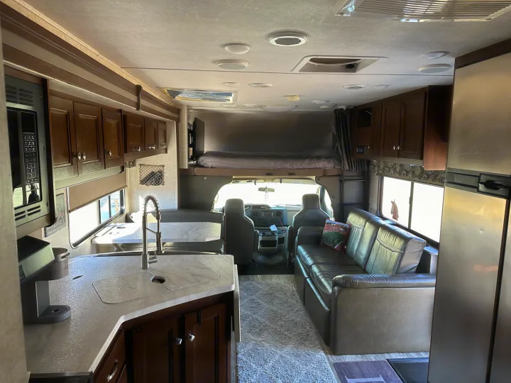 Bright, inviting RV rental interior showcasing kitchen, dining, and lounge areas, plus the spacious overhead bunk.. Forest River Sunseeker 2018