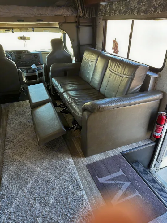 Step inside this cozy RV rental! Features a reclining leather sofa, overhead bunk, and front cabin views for comfortable travels.. Forest River Sunseeker 2018