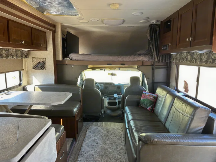 Bright and functional rv rental interior with dining booth, comfy sofa, and overhead bunk for comfortable travel.. Forest River Sunseeker 2018