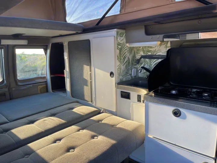 Inside an RV rental: view of the kitchenette, convertible sleeping area, and pop-top for extra space.. Ford E250 2008