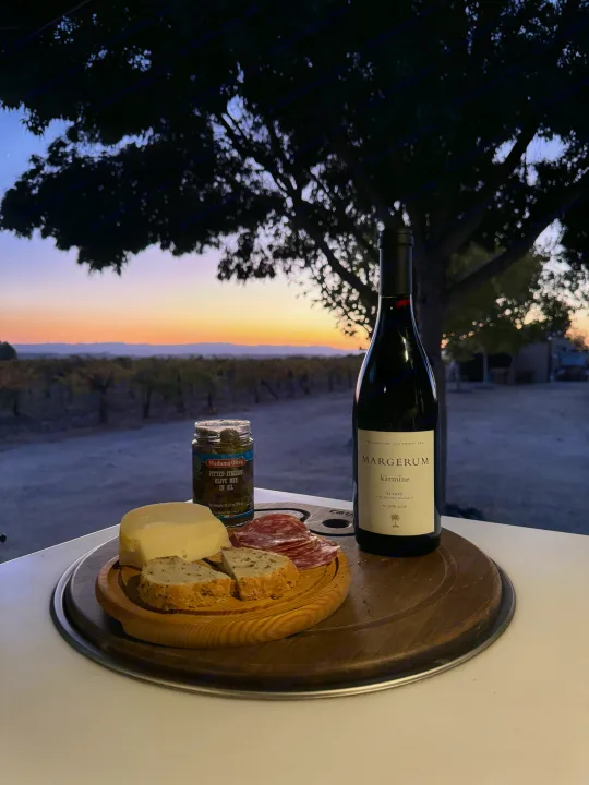 Sunset vineyard view from an RV rental with Margerum wine, cheese, olives, and charcuterie.. Storyteller Overland Storyteller Overland Class B 2023