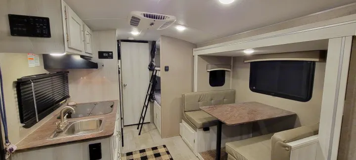 Full interior view of an rv rental, featuring a compact kitchen, bunk beds, and dinette seating area.. Forest River Rockwood Geo Pro 2022