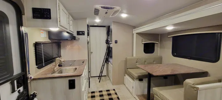 This RV rental interior features a light-toned kitchen, a dining area, and visible bunk beds, showcasing its spacious layout.. Forest River Rockwood Geo Pro 2022